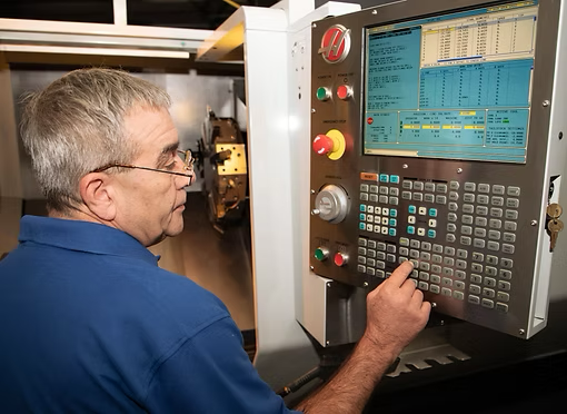 Technician operating a CNC machine control panel